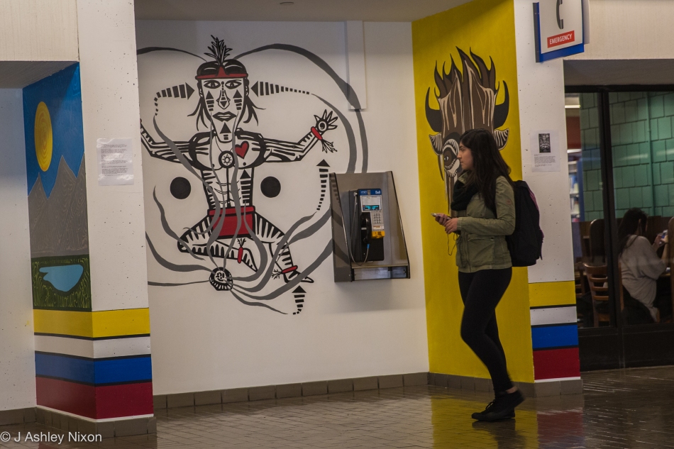 A student walking along Main Street checks out the paintings of Indigenous (Blackfoot) artist, Ryan Jason Allen Willert HeavyShield at Mount Royal University, Calgary, Canada. © J. Ashley Nixon